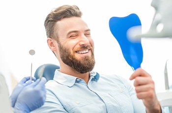 A patient checking his smile with a mirror