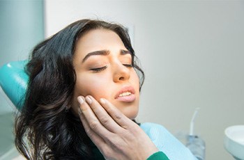 A patient holding her cheek due to dental pain
