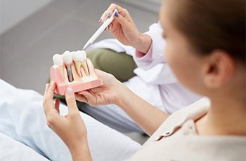 A patient holding onto a model of dental implants