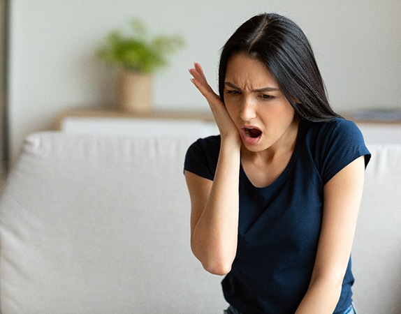 A woman suffering a dental emergency while sitting at home