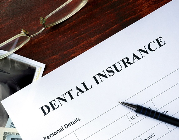 A dental insurance form set on a wooden table