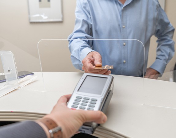 An obscured patient paying for their dental emergency care