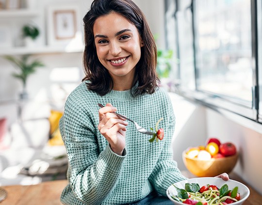 A young woman enjoying a healthy salad and smile