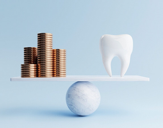 a pile of coins opposite a model tooth on a plank scale
