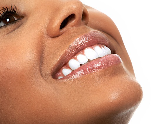 Eye-to-chin ¾ profile view of a woman with brown eyes and bright teeth smiling